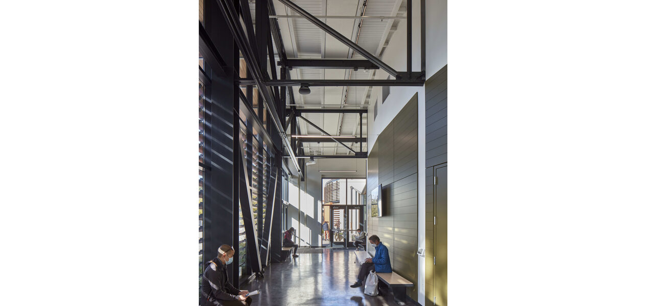 Hallway with a high ceiling where steel braces span between the walls and along the outside wall..