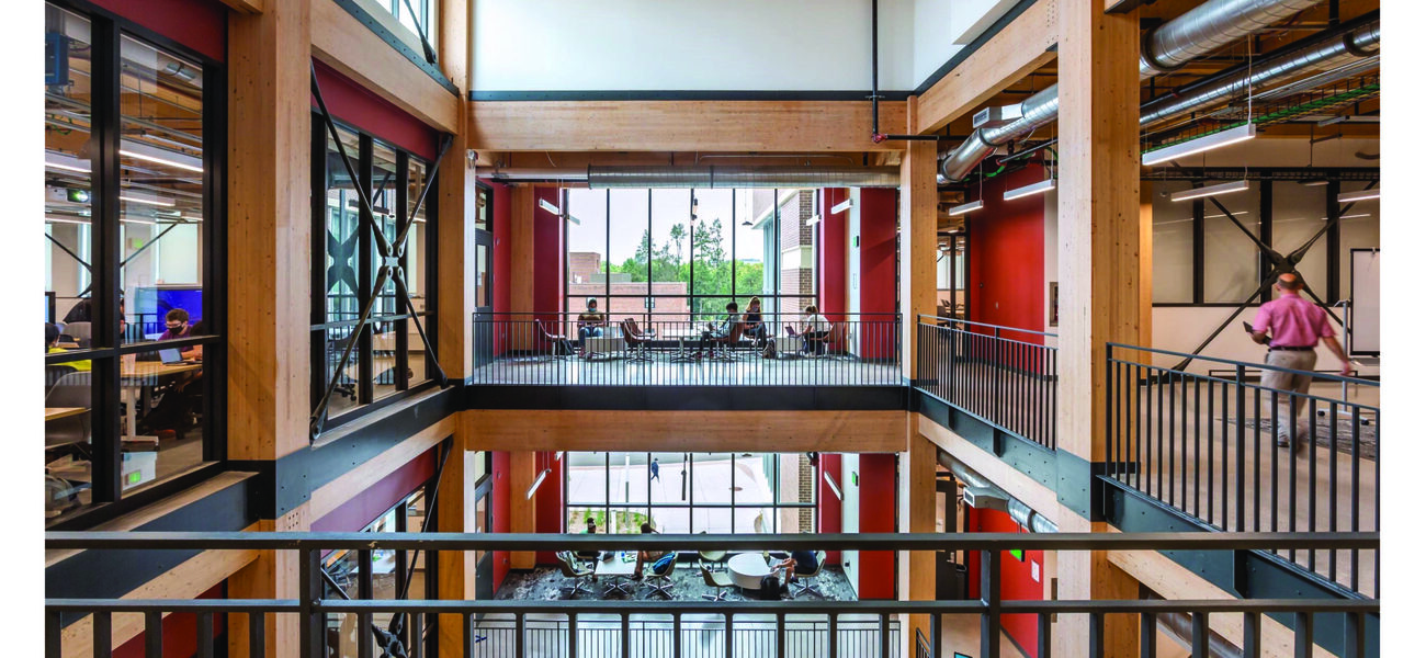 The second floor of an atrium constructed of large wooden beams and columns with steel railing.