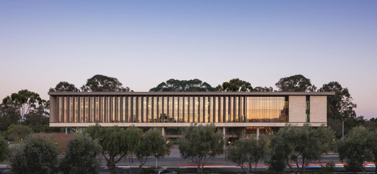 Long building clad in glass, raised among the trees