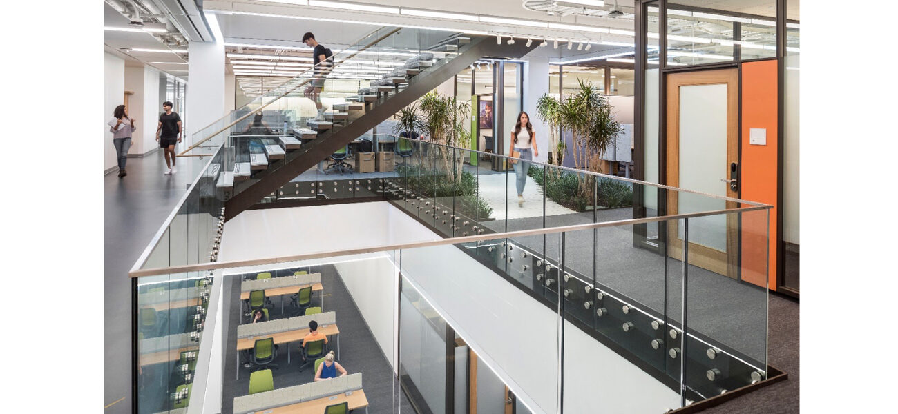 A man walks down a large staircase through a two-stpry atrium.