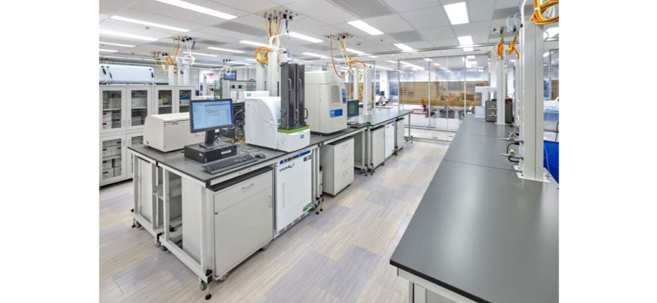 Lab space with cabinets mounted on wheels, and wires and hoses attached to the ceiling. 