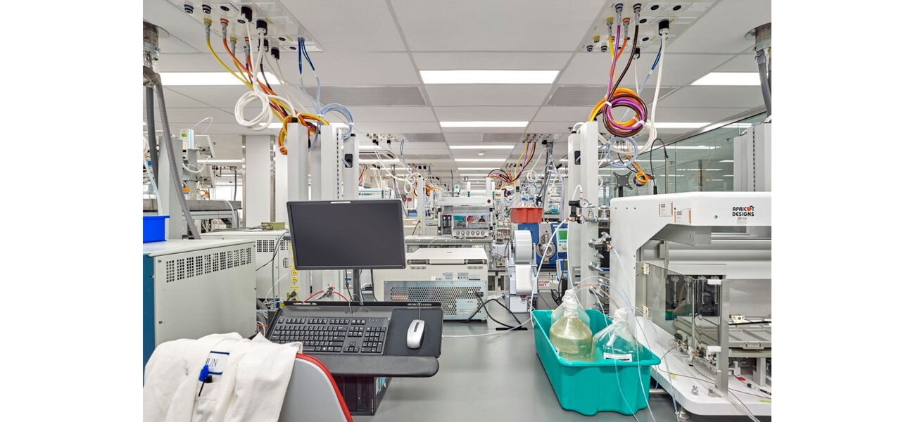 A row of lab benches attached to the ceiling with wires and hoses.