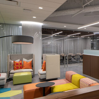 A room with one glass wall, soft seats and small tables